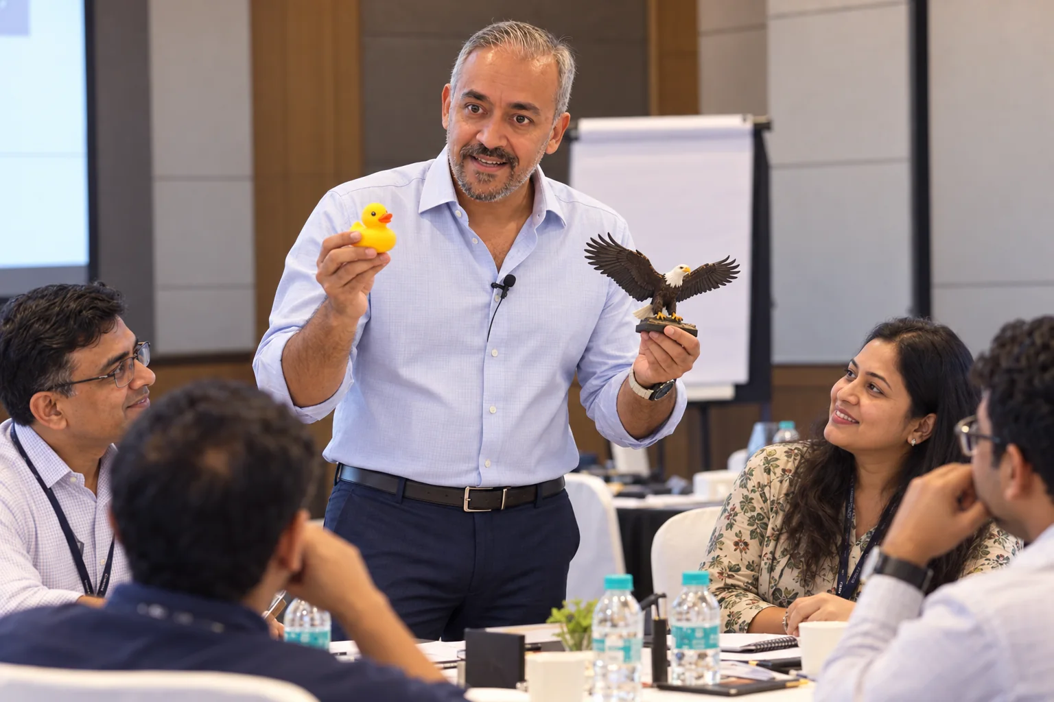 A facilitator demonstrates an activity with two objects while colleagues watch